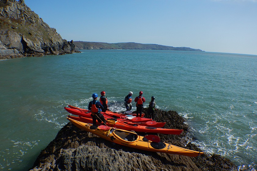 A group of sea kayakers on a rock